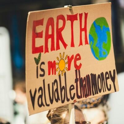 Sign reading 'Earth is more valuable than money' at a climate protest outdoors.